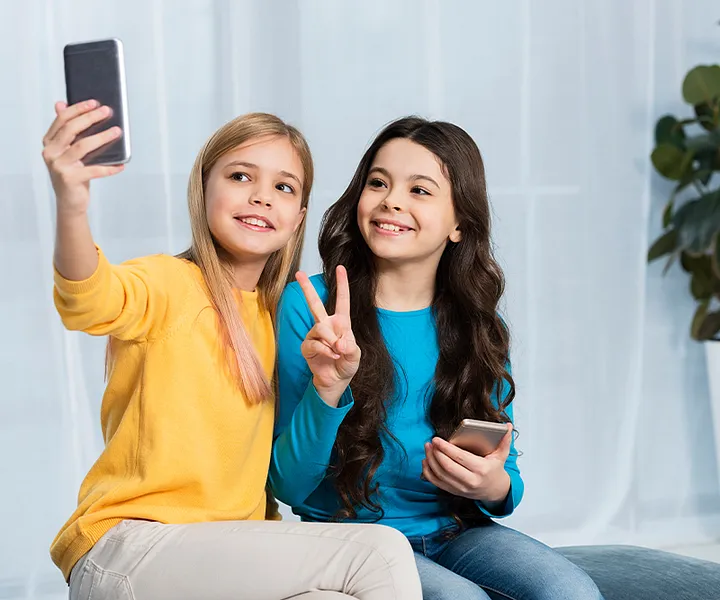 Two girls sitting and taking a selfie on their smartphone.